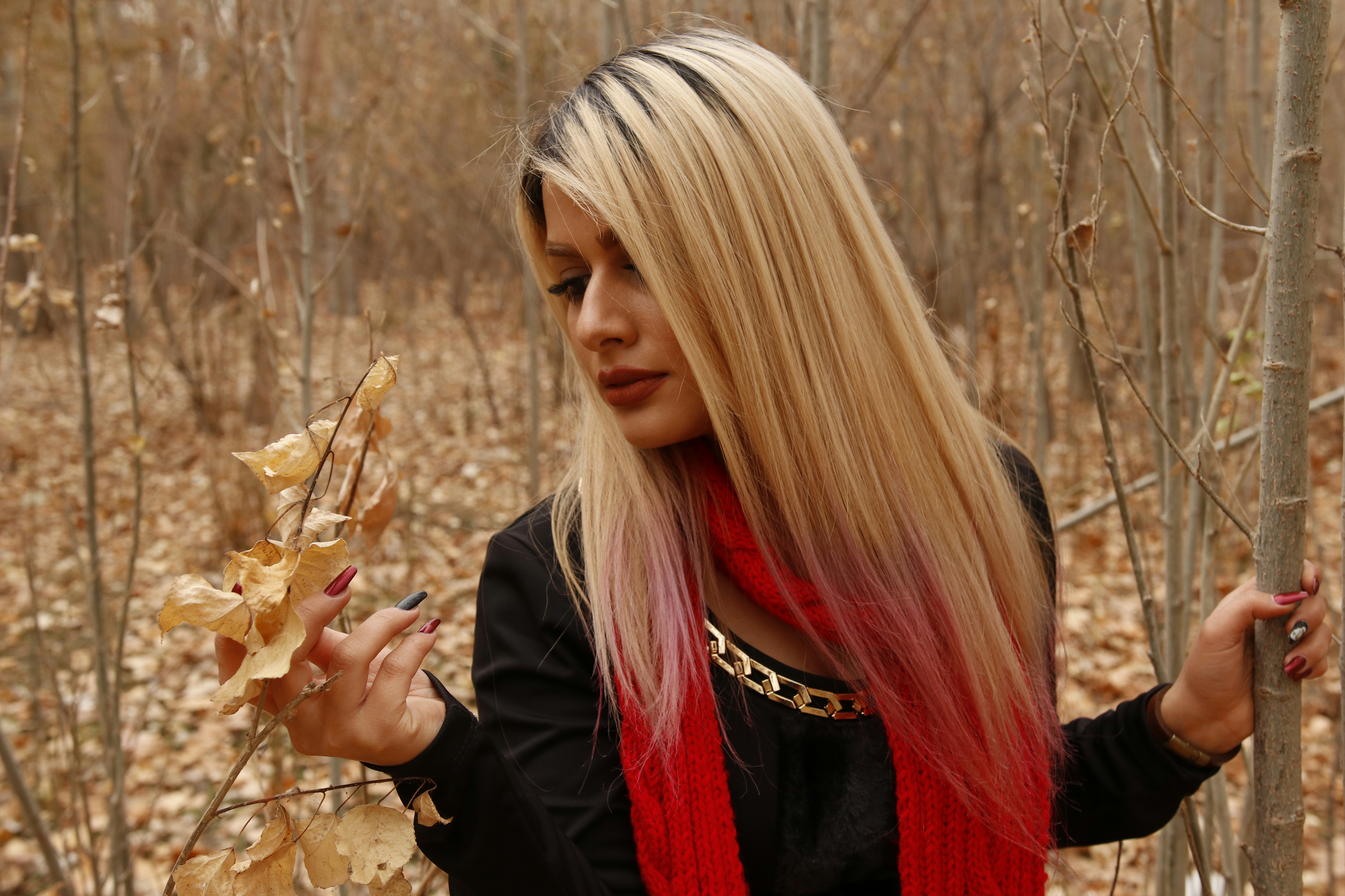 a woman with long blonde hair standing in a forest