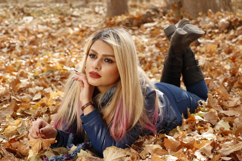 a woman laying on the ground covered in leaves