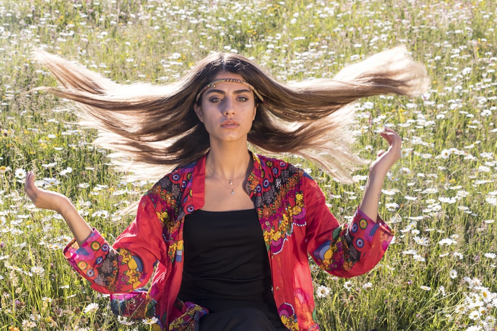 a woman with long hair sitting in a field of flowers