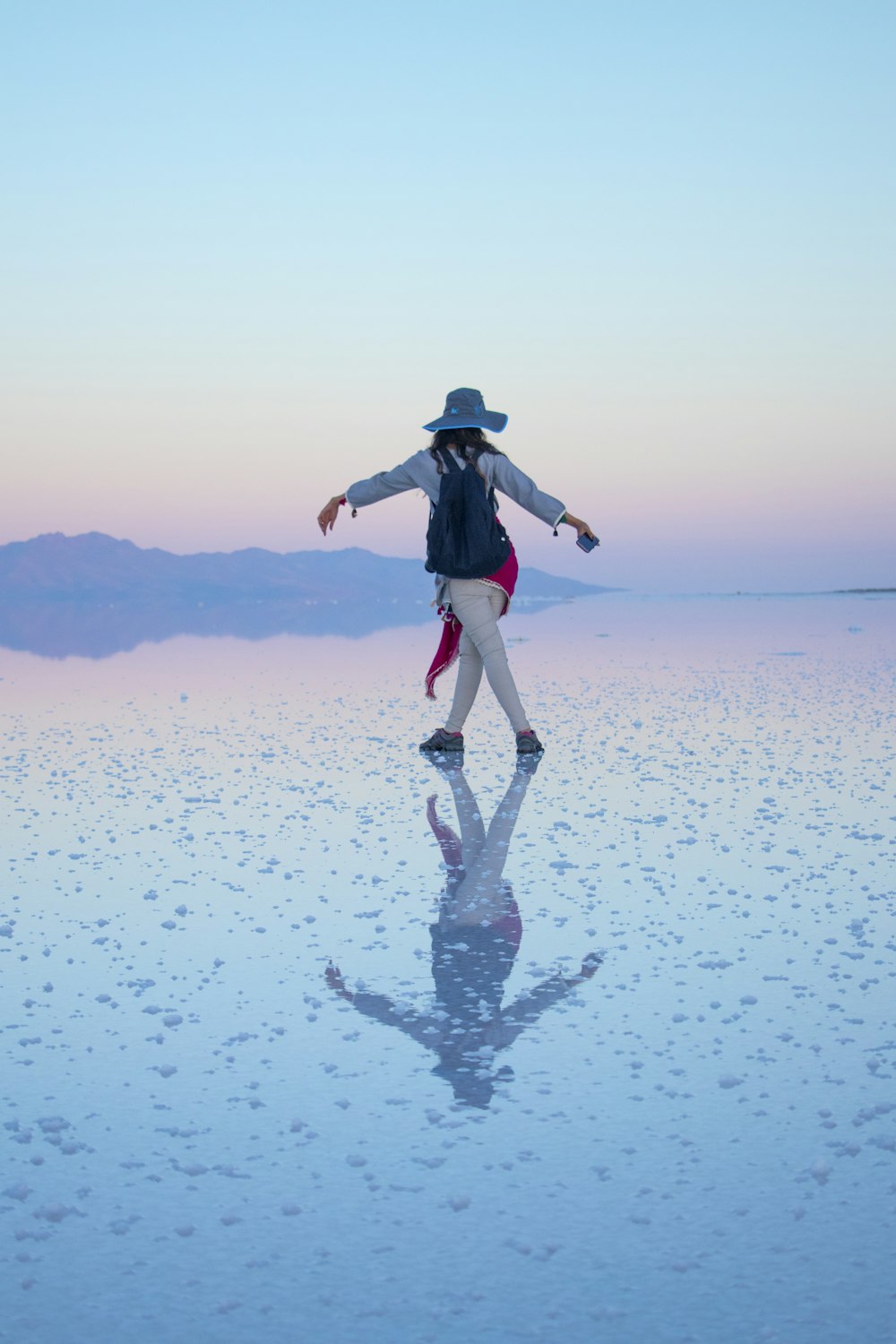 a woman in a hat is standing on the water