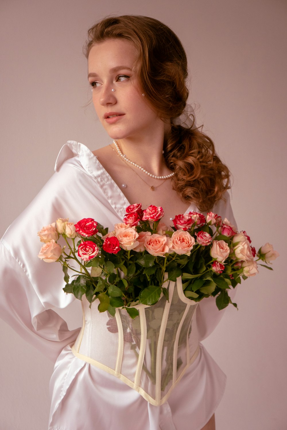Une femme en robe blanche tenant un bouquet de roses