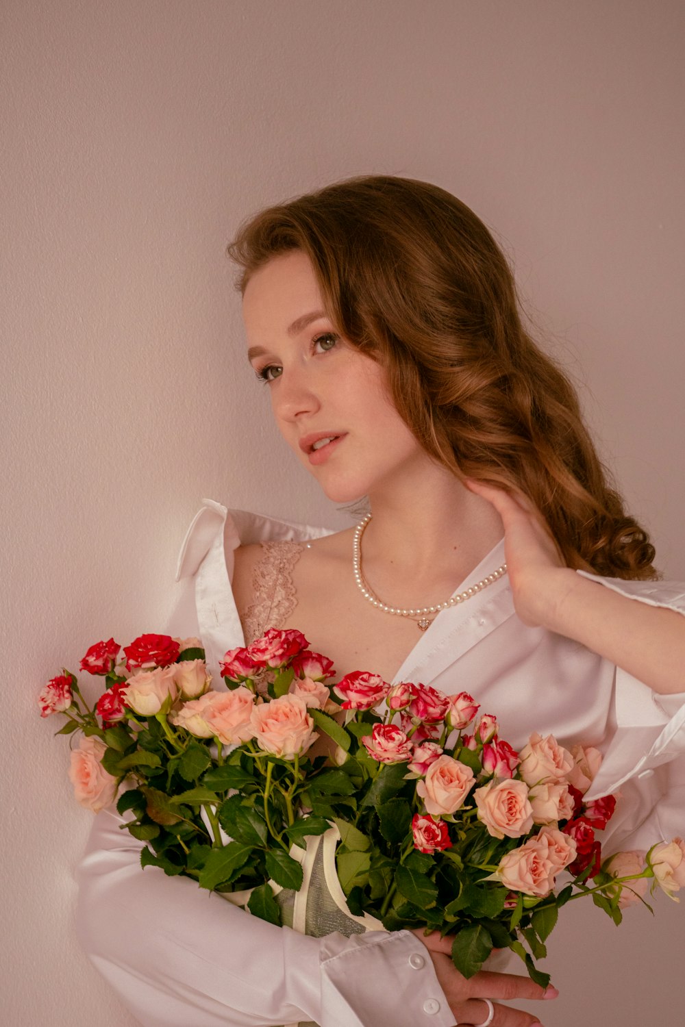 a woman in a white dress holding a bouquet of roses