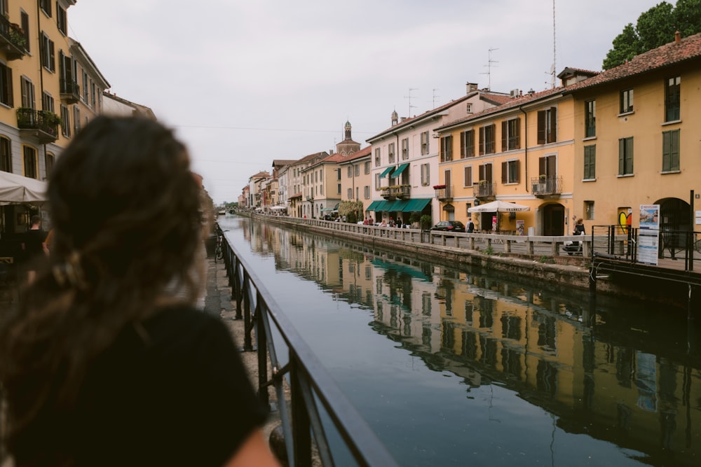 a woman looking out over a canal in a city