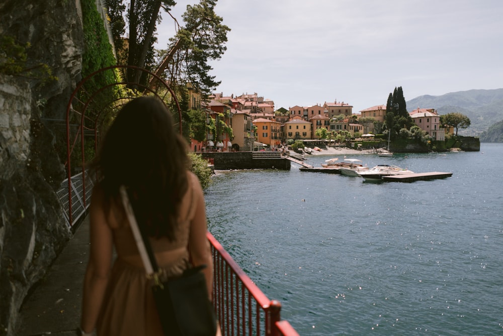 a woman standing on a bridge looking at boats in the water