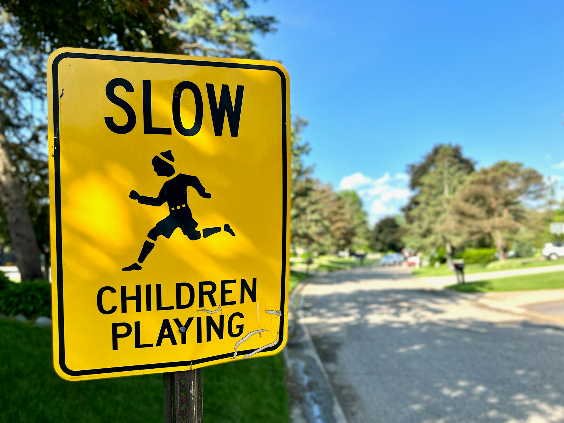 a yellow slow children's playing sign sitting on the side of a road