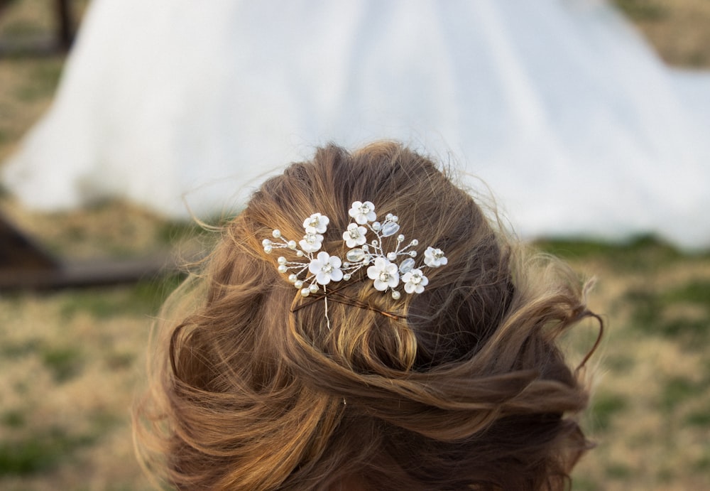 um close up do cabelo de uma mulher com um vestido de noiva no fundo