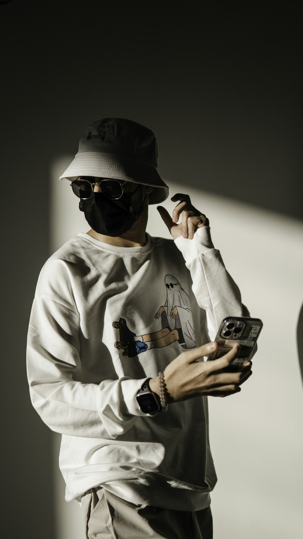 a man in a white sweatshirt and hat holding a cell phone