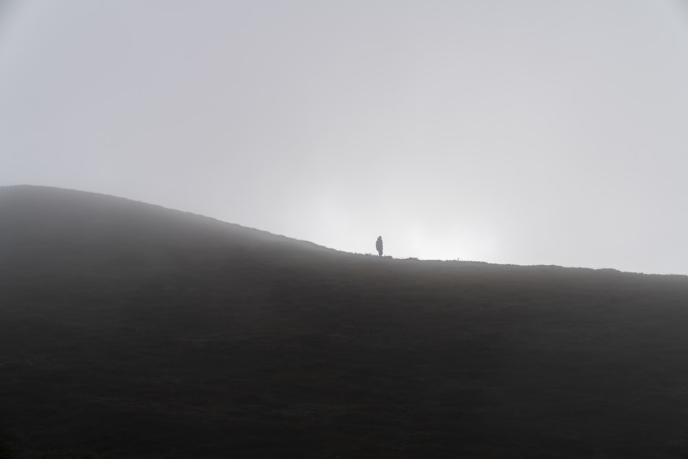 Eine Person, die auf einem Hügel steht und die Sonne hinter sich hat