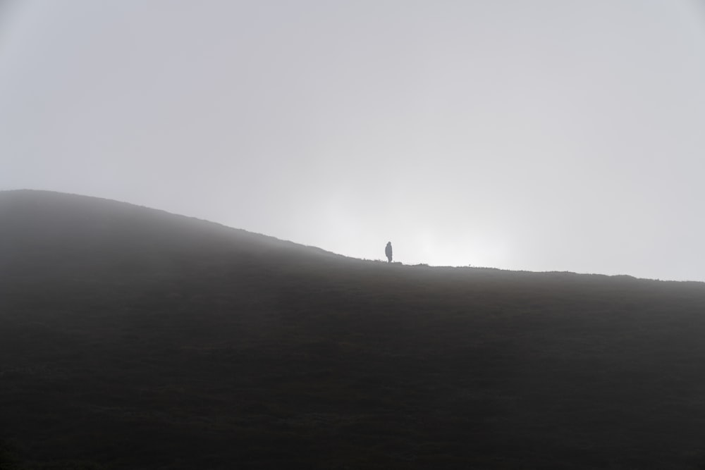 a person standing on a hill with the sun behind them