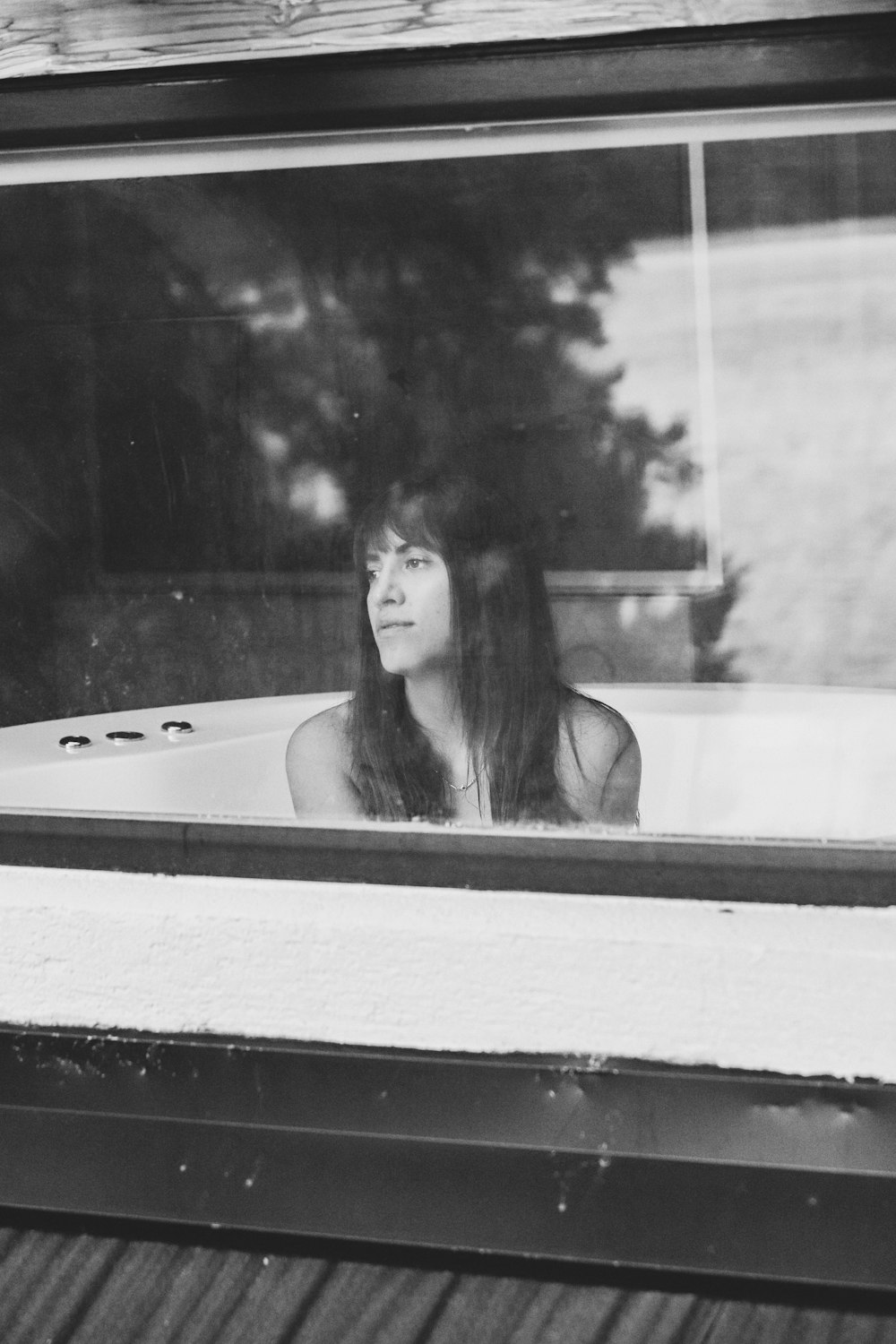 a woman sitting in a bathtub looking out the window