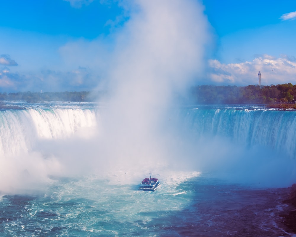 a boat in a body of water near a waterfall