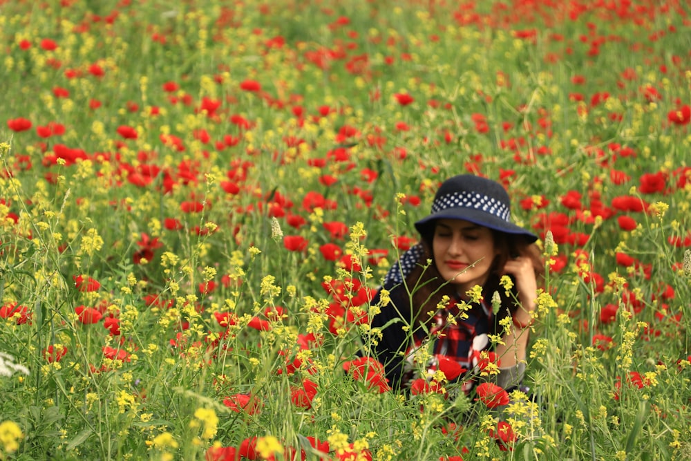 a woman sitting in a field of red and yellow flowers