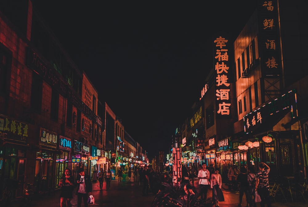 a group of people walking down a street at night