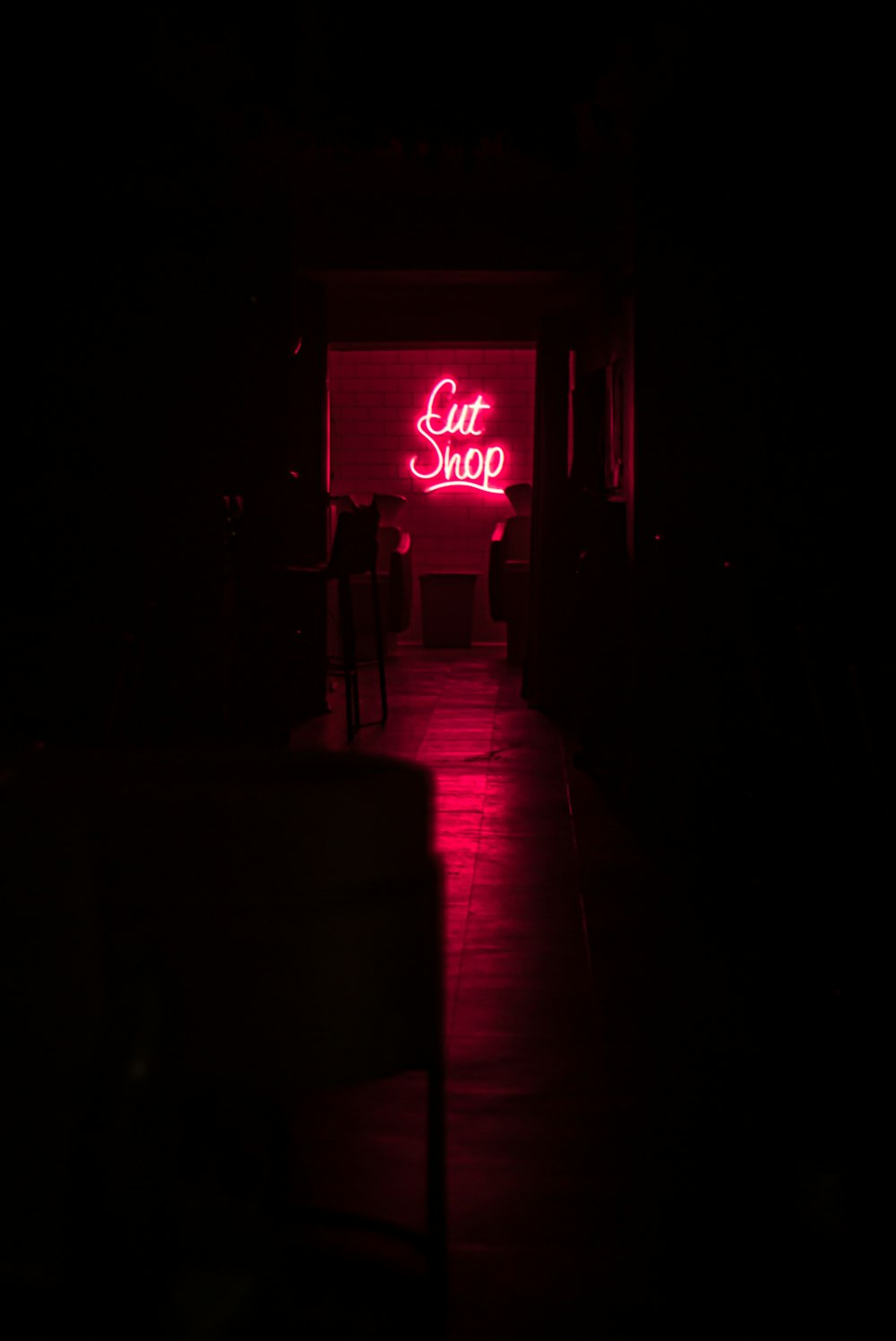 Un couloir sombre avec une enseigne au néon qui dit Cut Shop