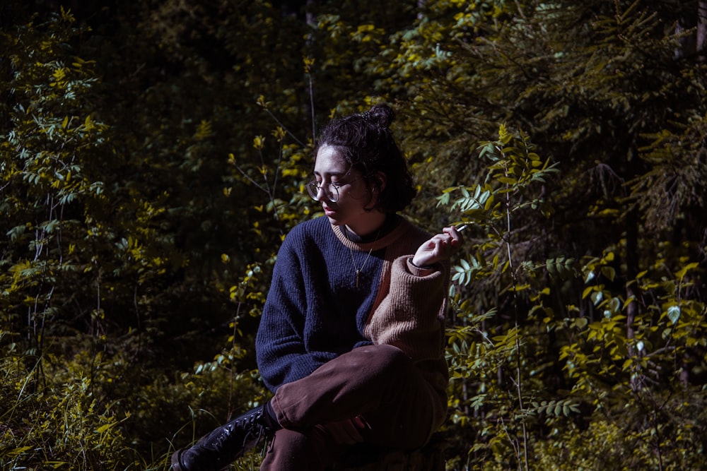 a woman sitting on a rock in the woods