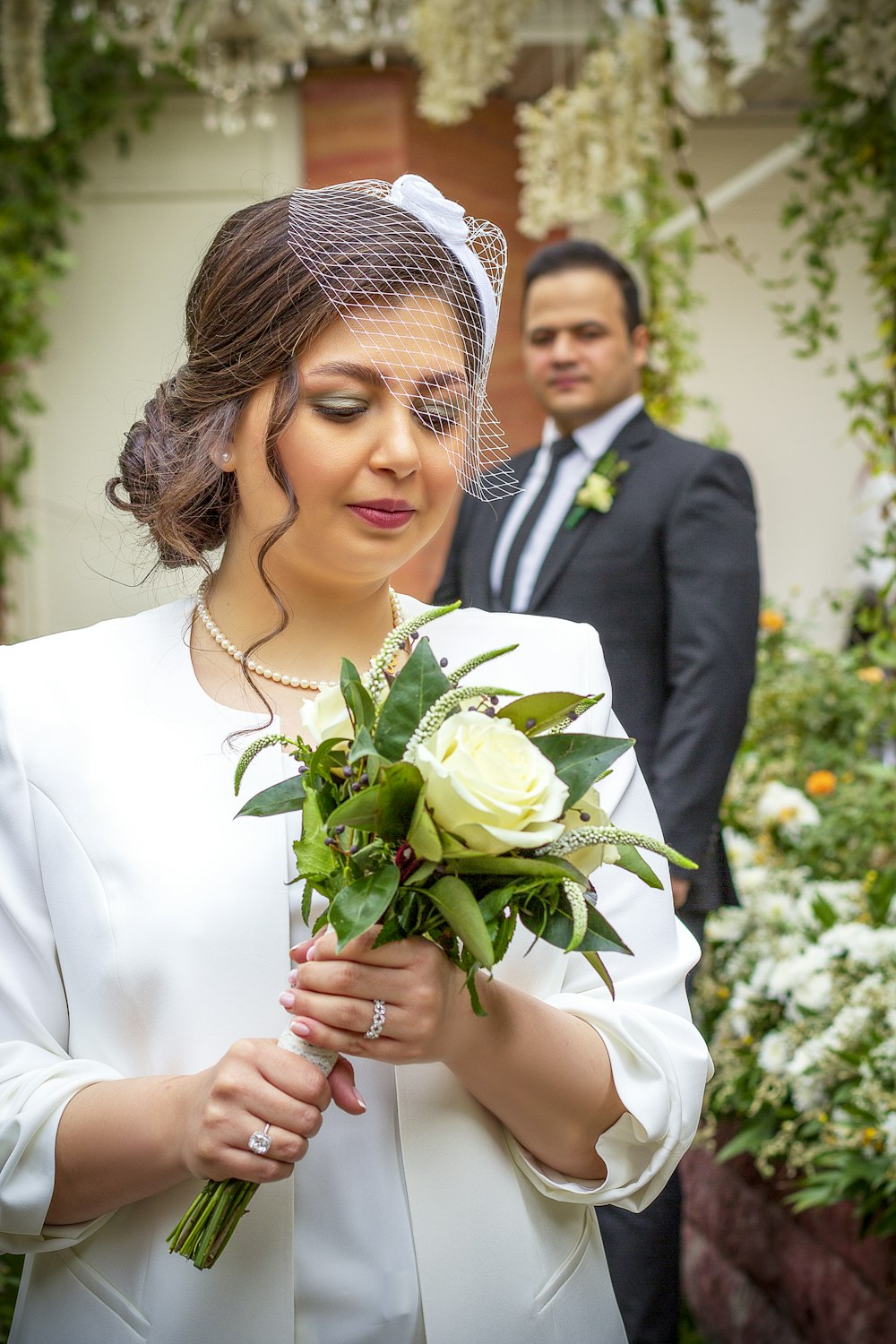 a woman holding a bouquet of flowers next to a man in a suit