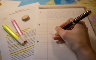 a person writing on a notebook with a pen