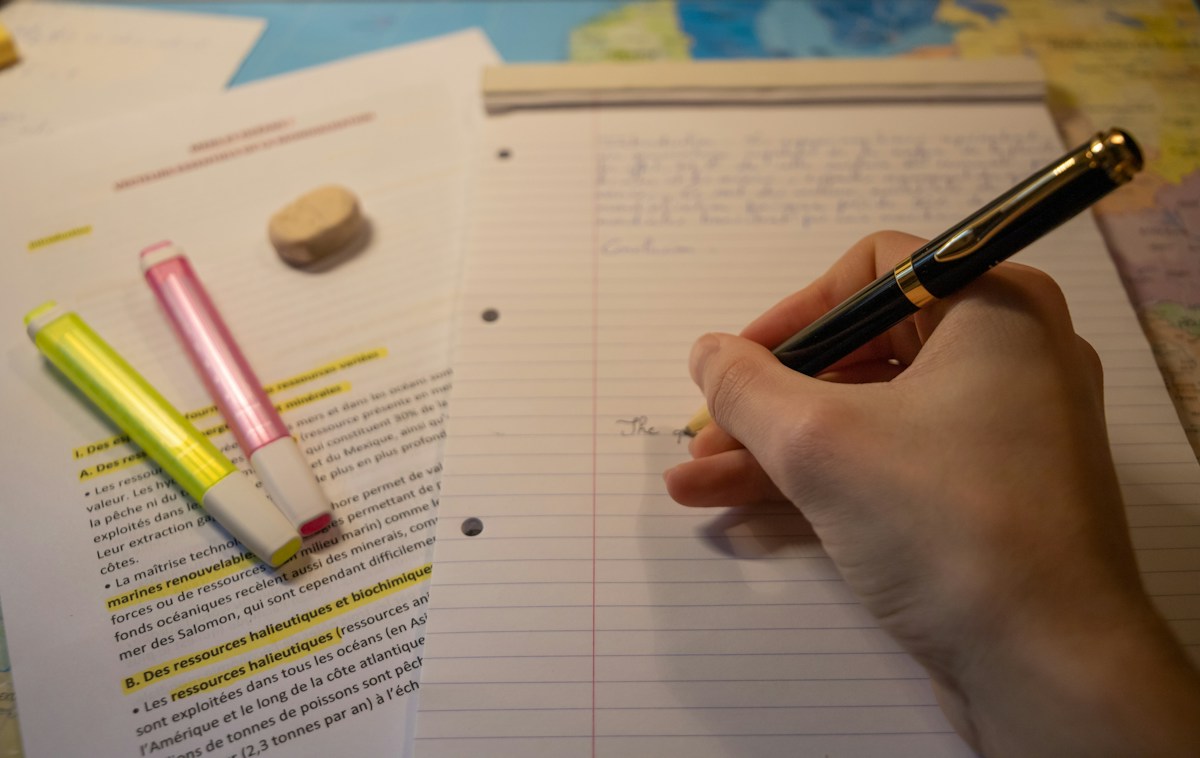Person writing community service ideas in a notebook with a pen