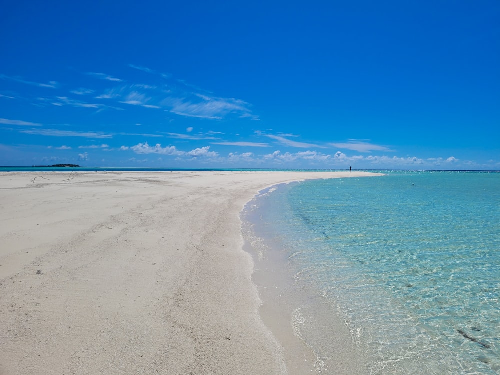 a sandy beach with clear blue water on a sunny day