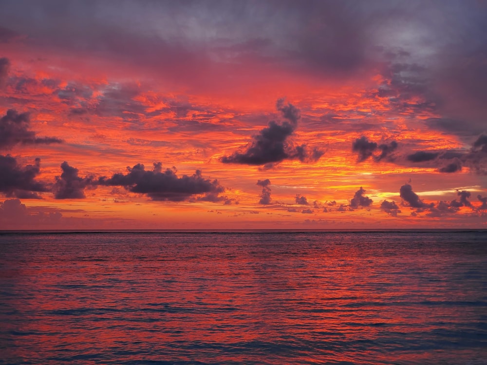 a beautiful sunset over the ocean with clouds