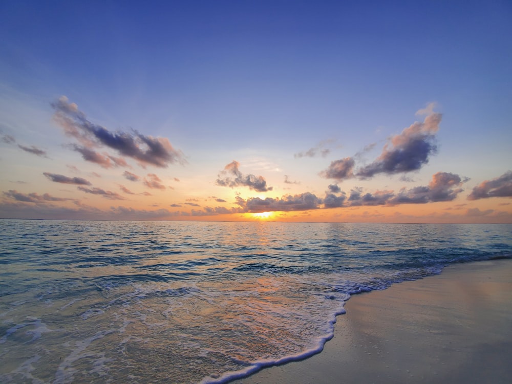 the sun is setting over the water at the beach