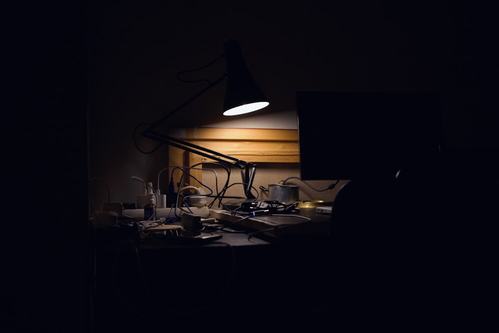 a dark room with a desk lamp and a computer