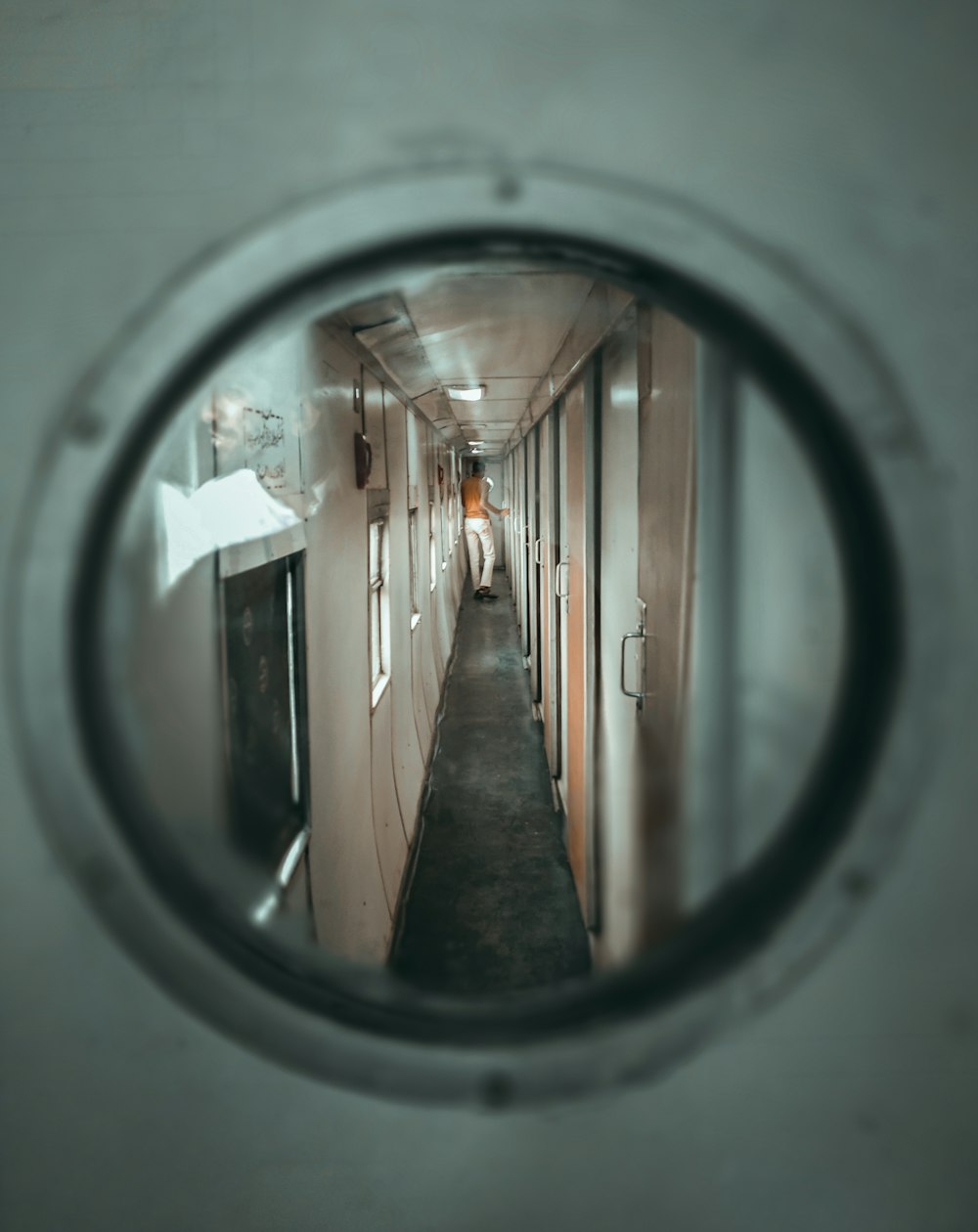 a narrow hallway is seen through a round mirror