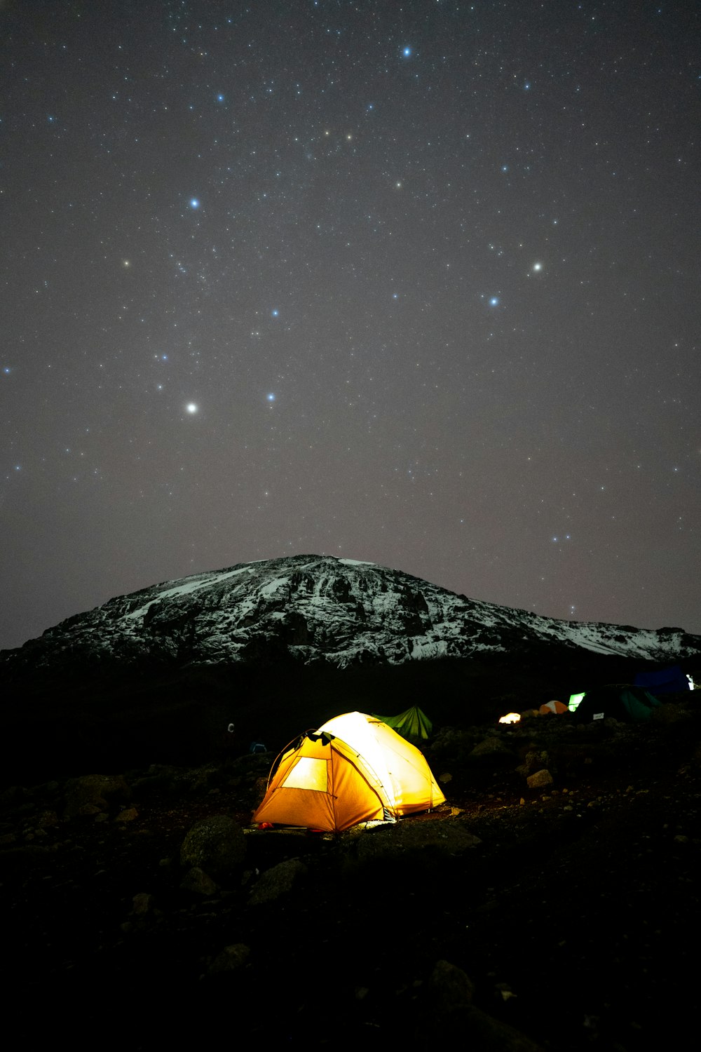 a tent pitched up on a mountain under a night sky filled with stars