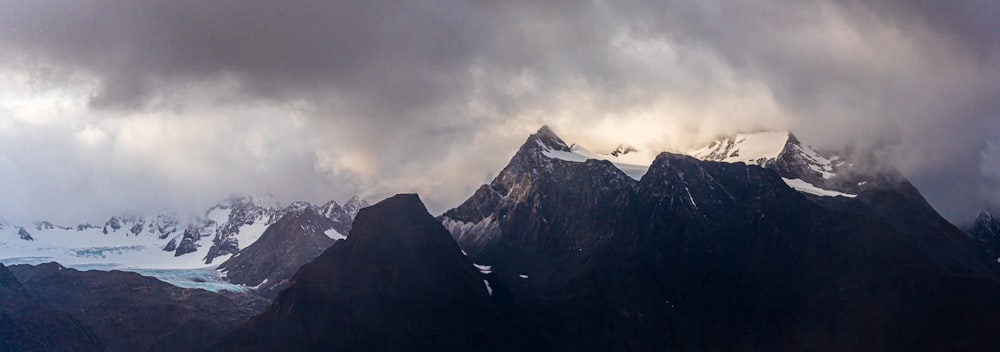 a group of mountains with snow on them under a cloudy sky