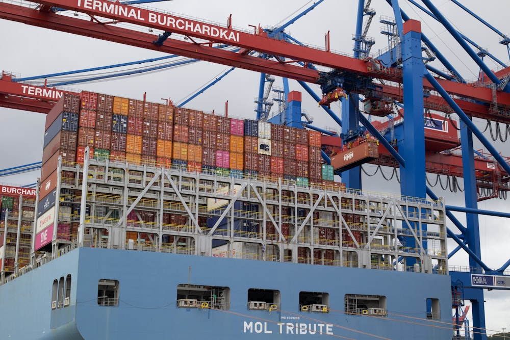 a large cargo ship loaded with containers under a crane