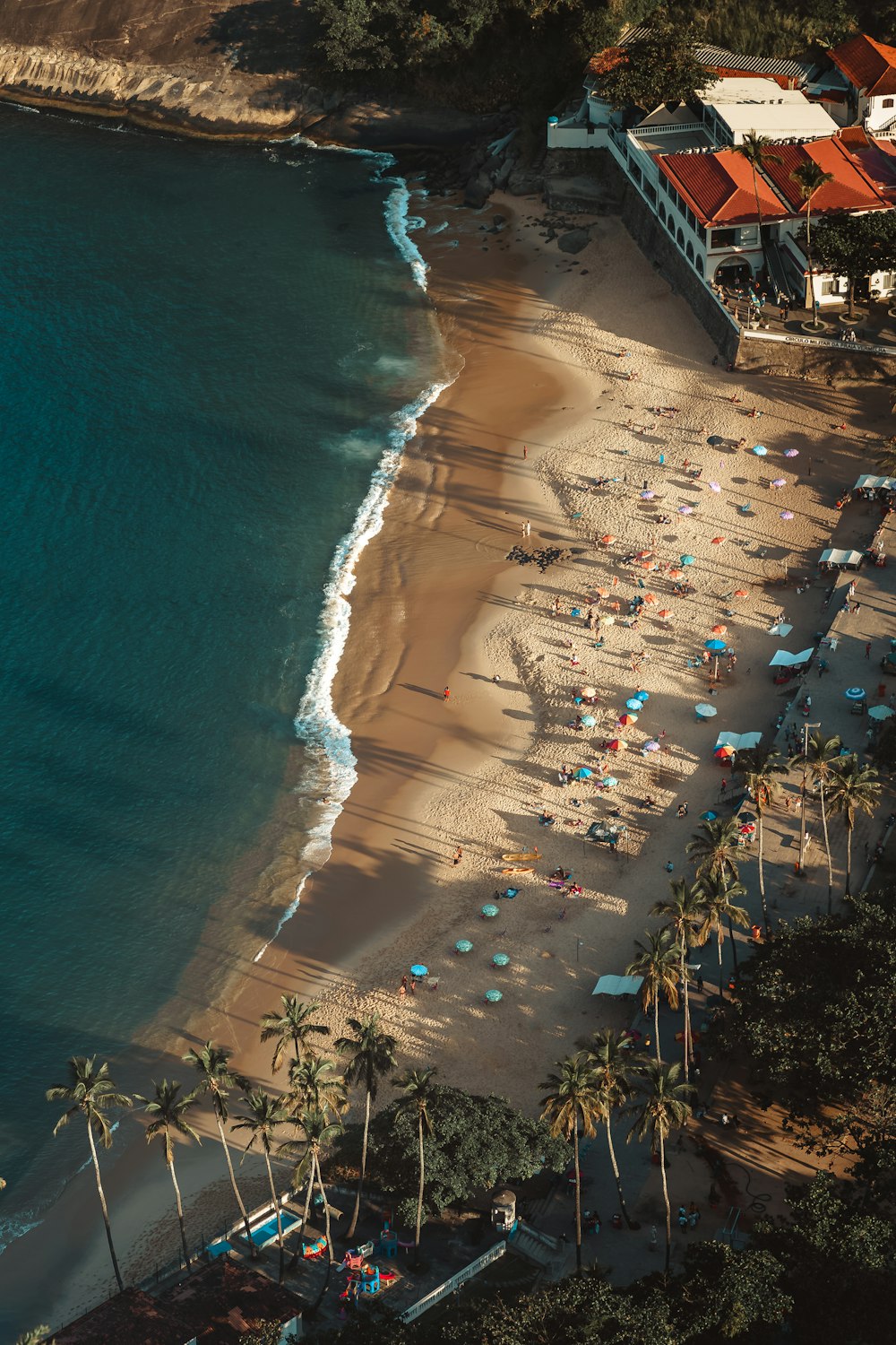 an aerial view of a beach with umbrellas and chairs