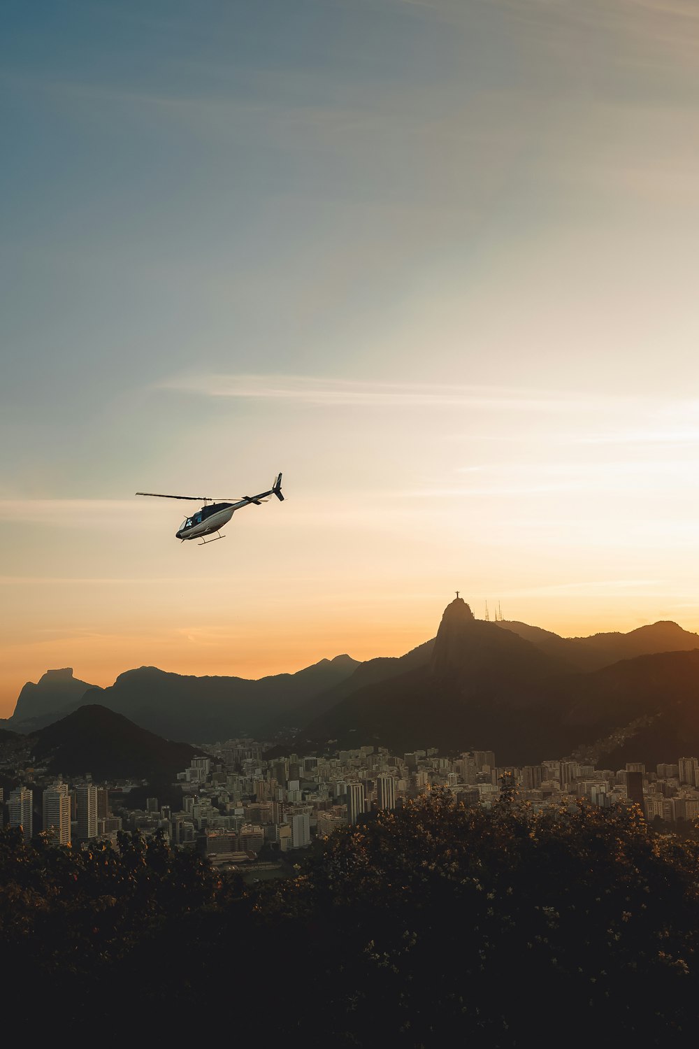 um helicóptero voando sobre uma cidade ao pôr do sol