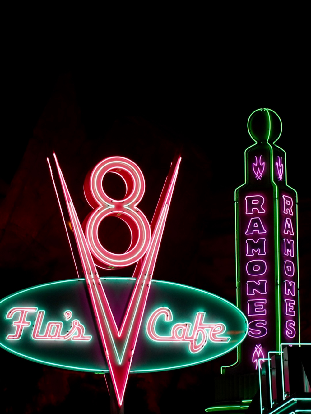 a neon sign for a restaurant with a clock tower in the background