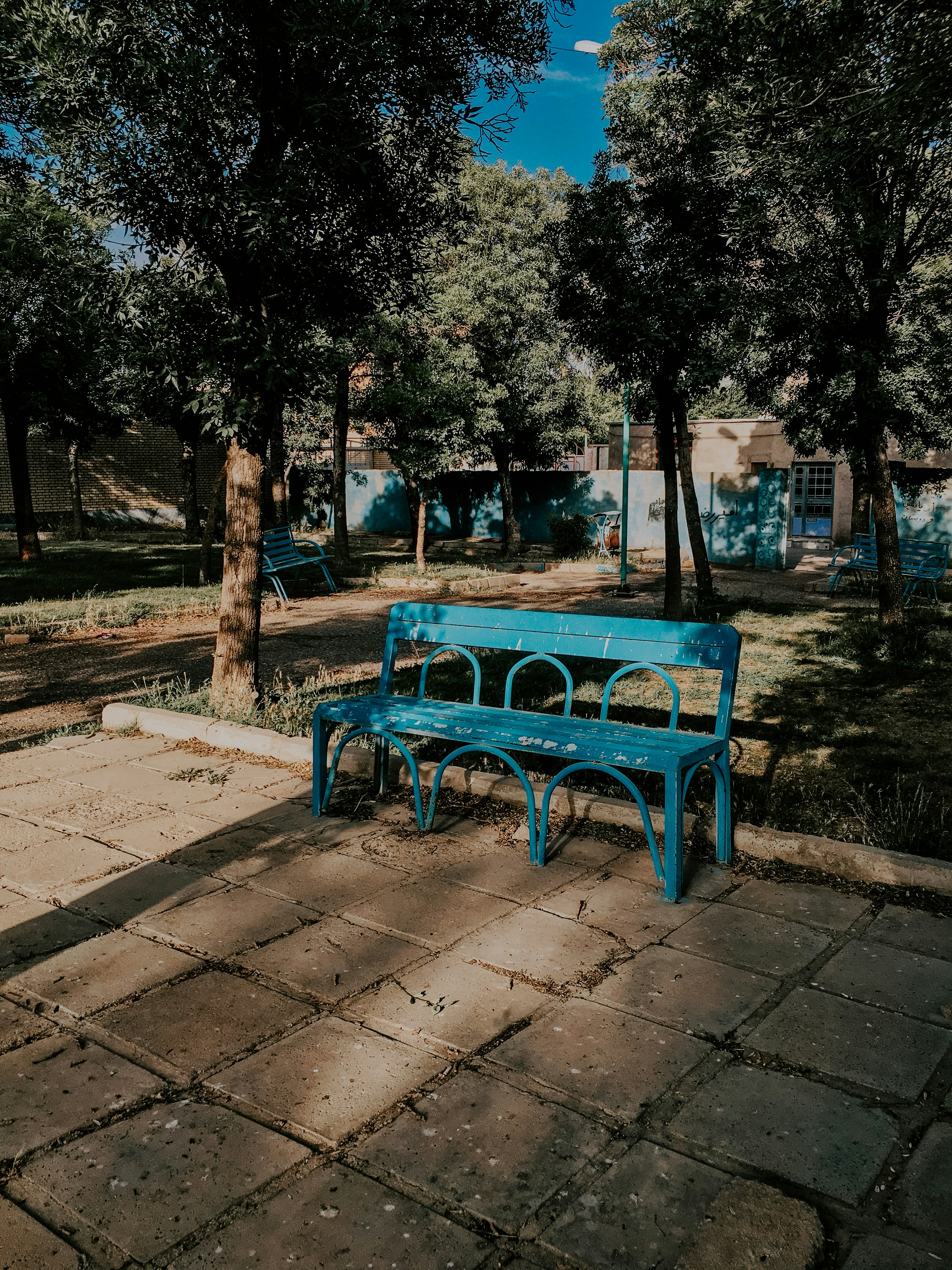 an empty park bench next to a fence