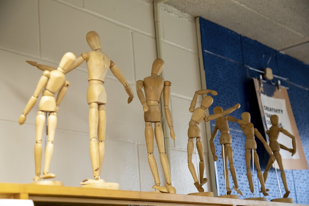 several wooden mannequins on a shelf in a room