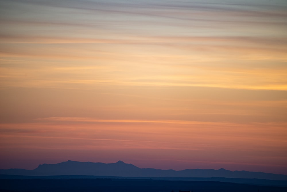 a plane flying in the sky with a sunset in the background