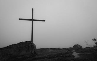 a black and white photo of a cross on a hill