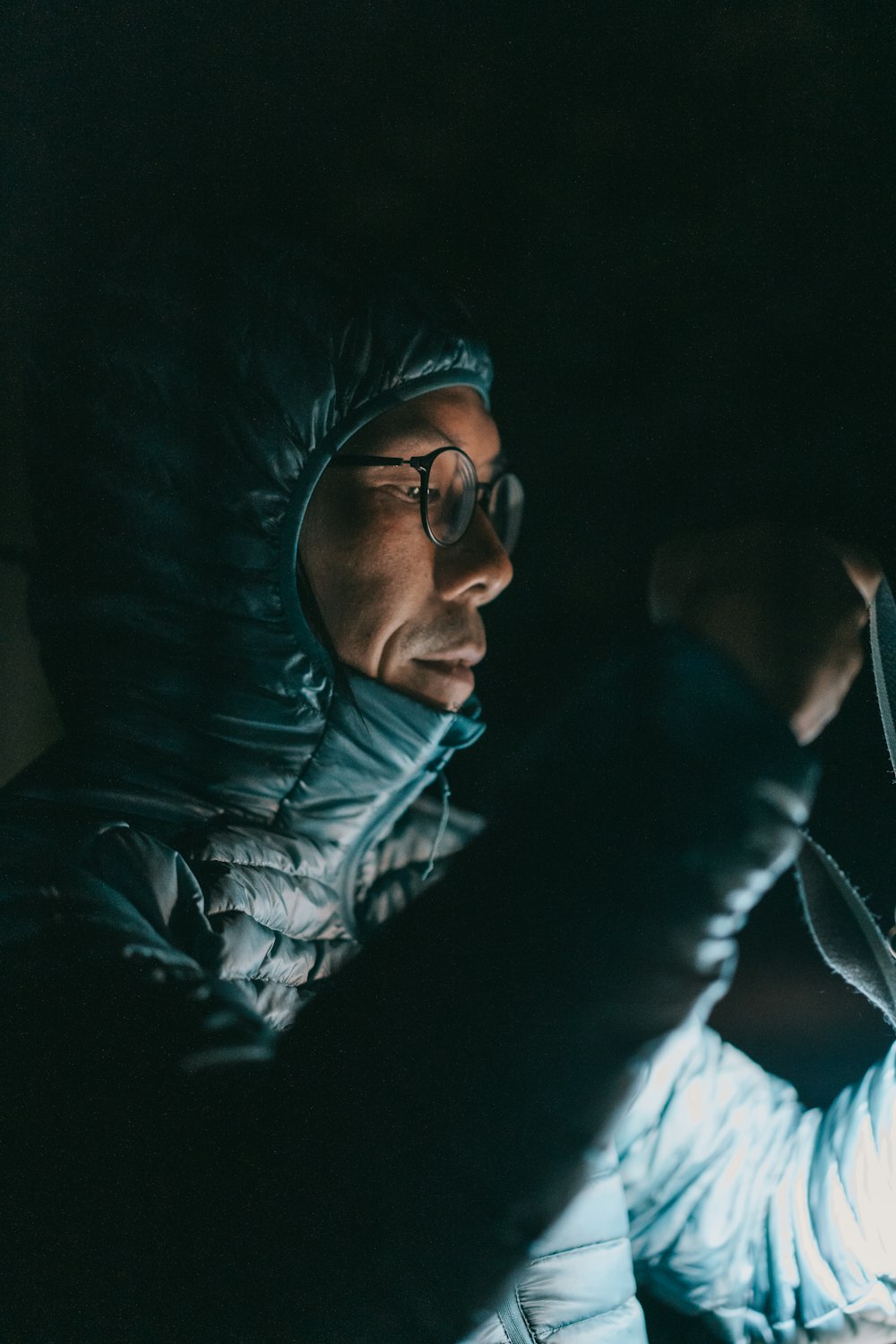 a woman in a hooded jacket holding a lit candle