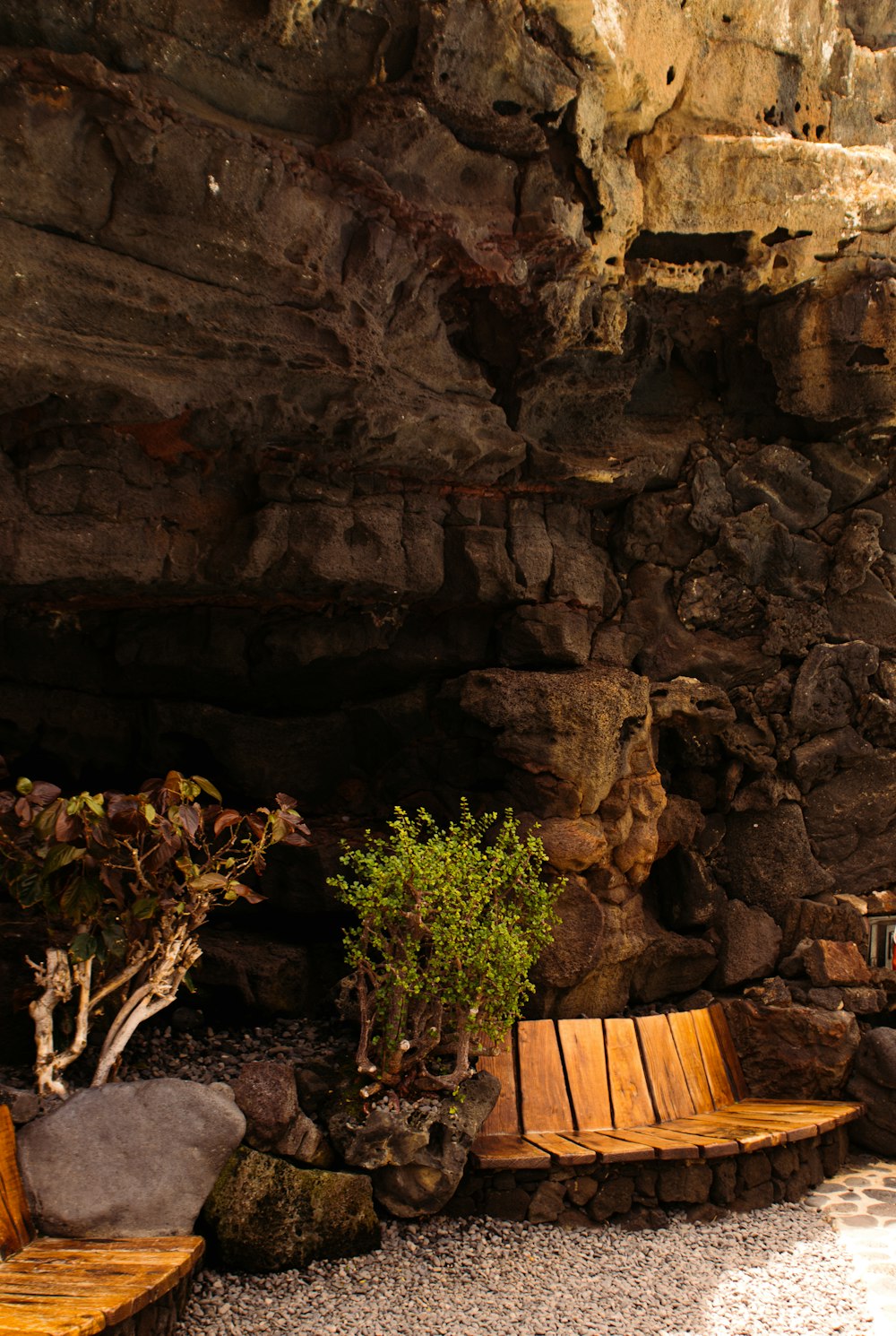 a couple of wooden benches sitting next to a stone wall