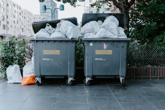 a couple of trash cans sitting on top of a sidewalk