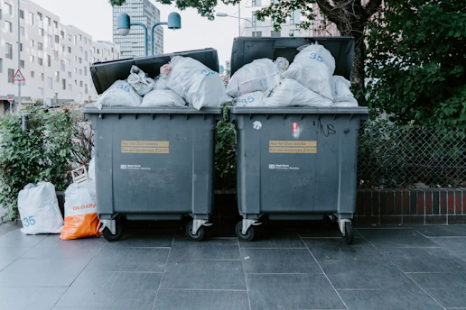 a couple of trash cans sitting on top of a sidewalk