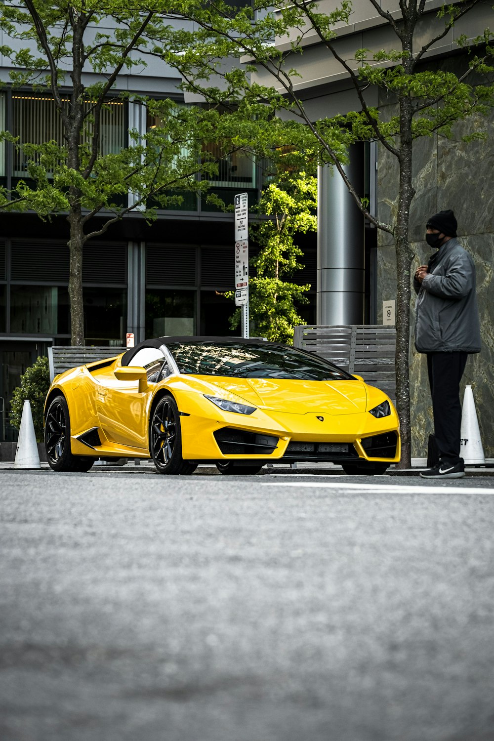 a man standing next to a yellow sports car