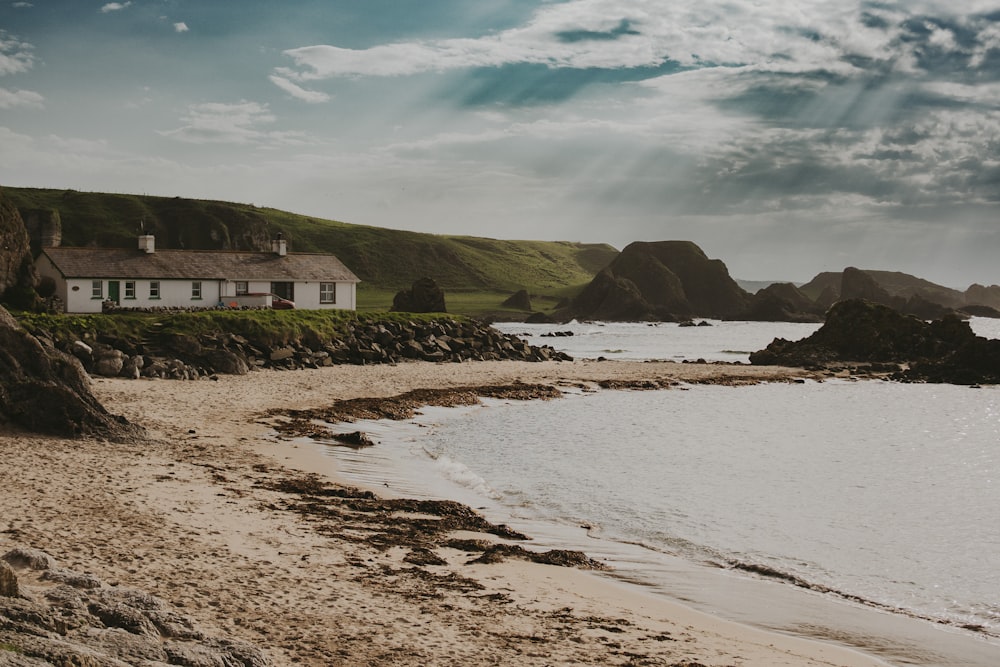 a house sitting on top of a beach next to a body of water