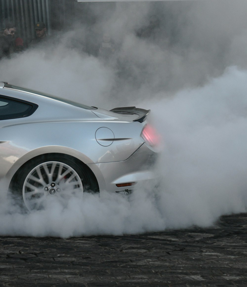 a silver sports car with a lot of smoke coming out of it