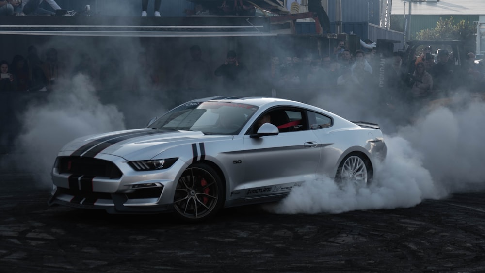 a silver mustang car with smoke coming out of it