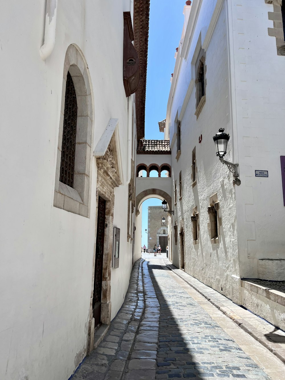 a narrow cobblestone street lined with white buildings