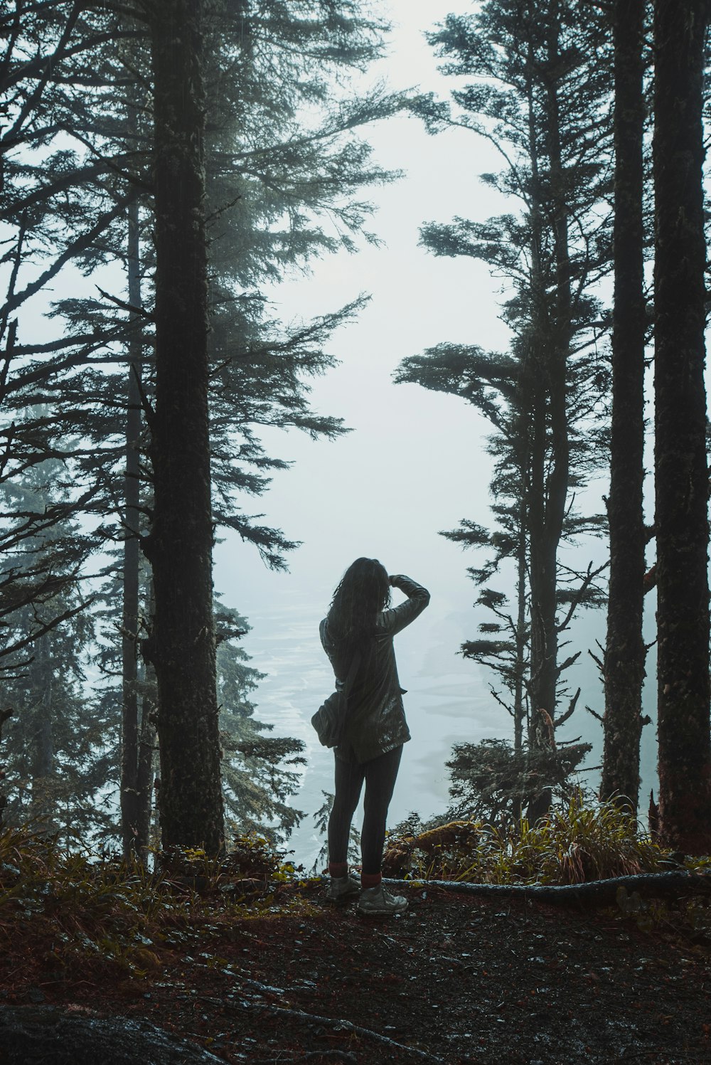 a woman standing in the middle of a forest