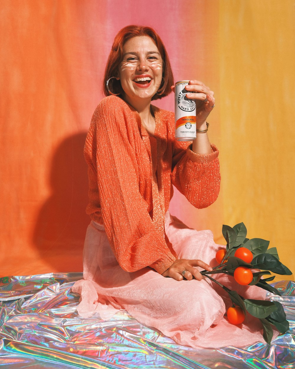a woman sitting on the ground holding a can of beer