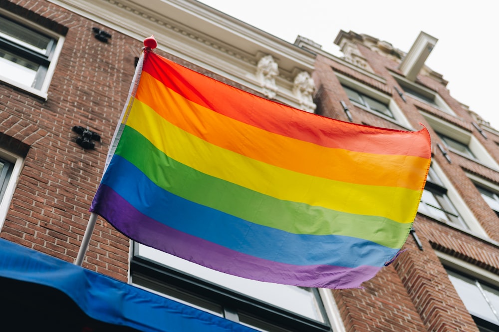 Una bandera del arco iris ondea frente a un edificio