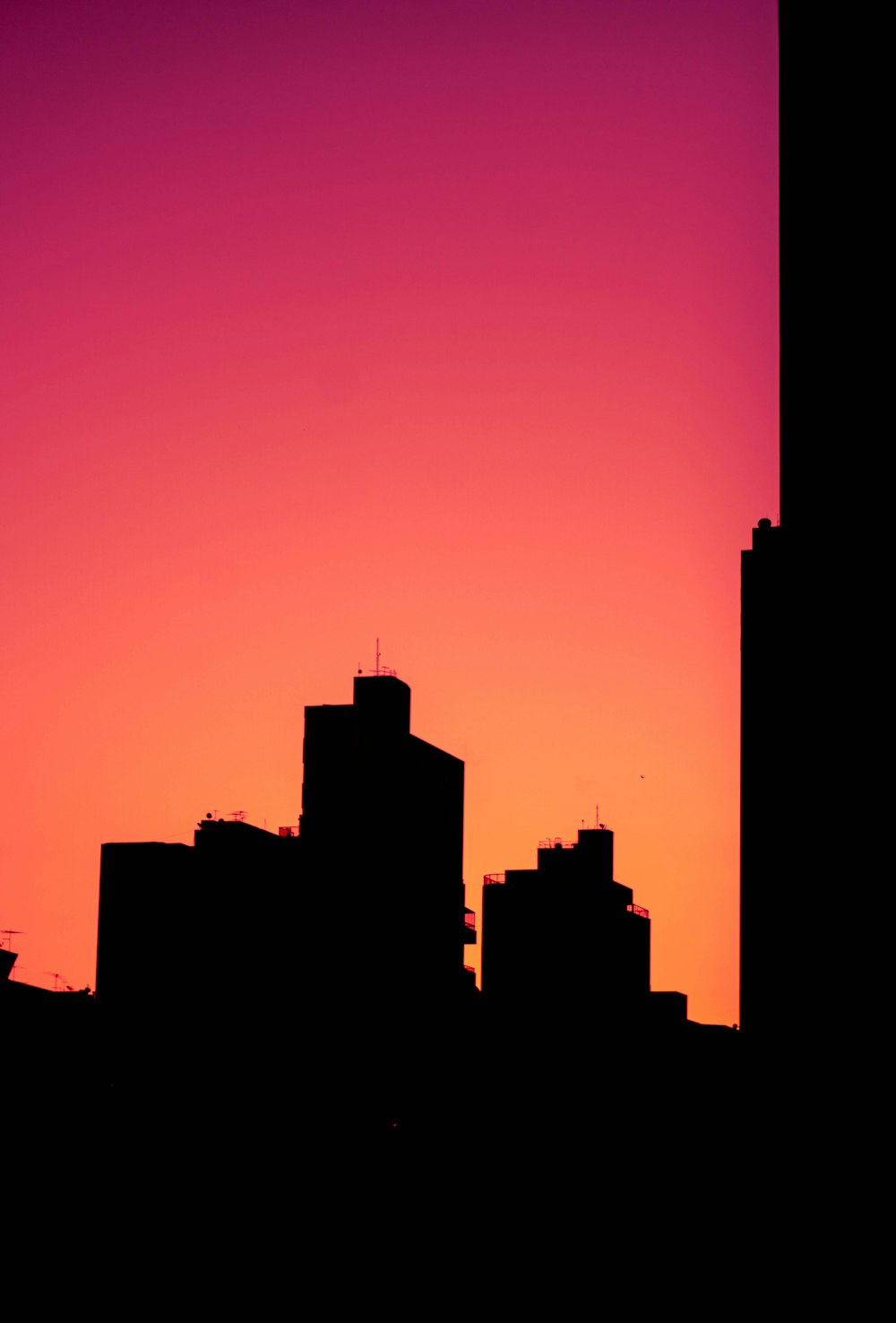 the silhouette of a city skyline at sunset